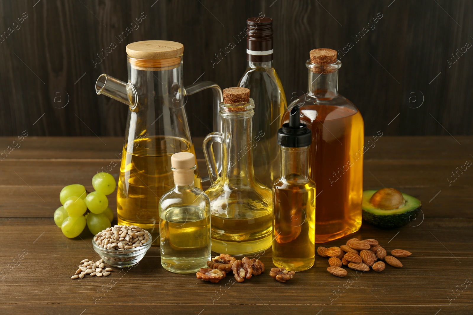 Photo of Vegetable fats. Different oils in glass bottles and ingredients on wooden table