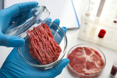 Photo of Scientist holding Petri dish with minced cultured meat in laboratory, closeup. Space for text