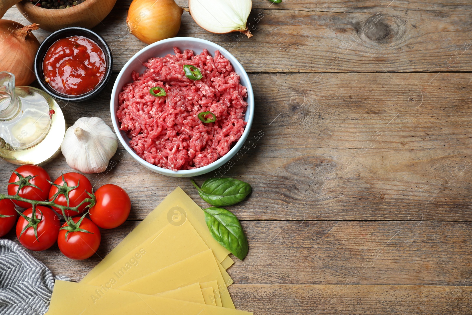 Photo of Fresh lasagna ingredients on wooden table, flat lay. Space for text