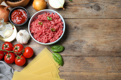 Photo of Fresh lasagna ingredients on wooden table, flat lay. Space for text