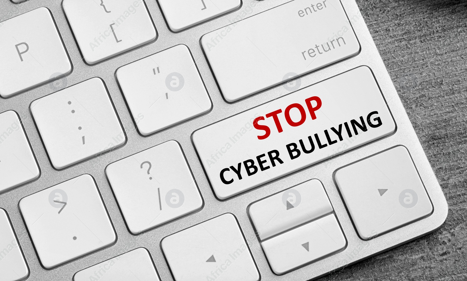 Image of Top view of computer keyboard with phrase STOP CYBER BULLYING on white button, closeup