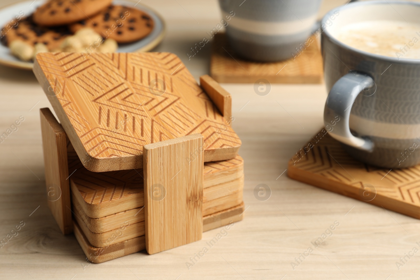 Photo of Many stylish wooden cup coasters and mugs on table