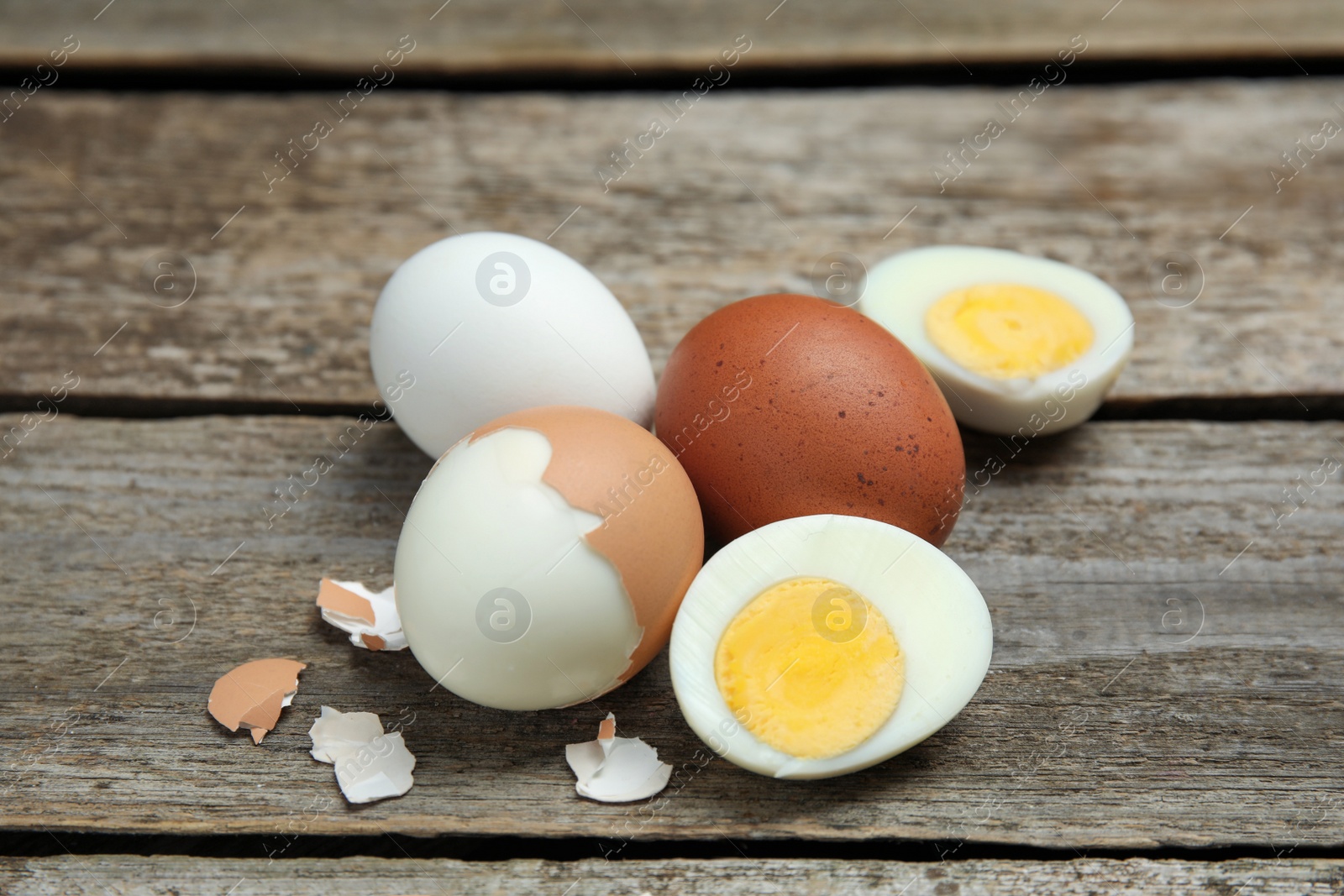 Photo of Hard boiled eggs and pieces of shell on wooden table