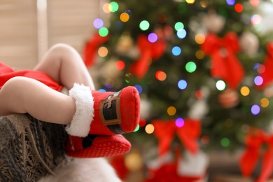 Photo of Cute baby in Christmas costume at home, focus on legs