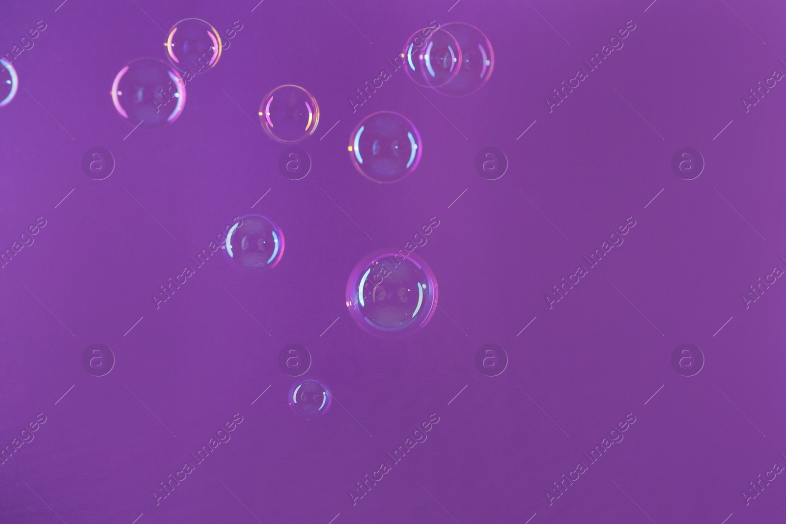 Photo of Beautiful transparent soap bubbles on violet background, space for text