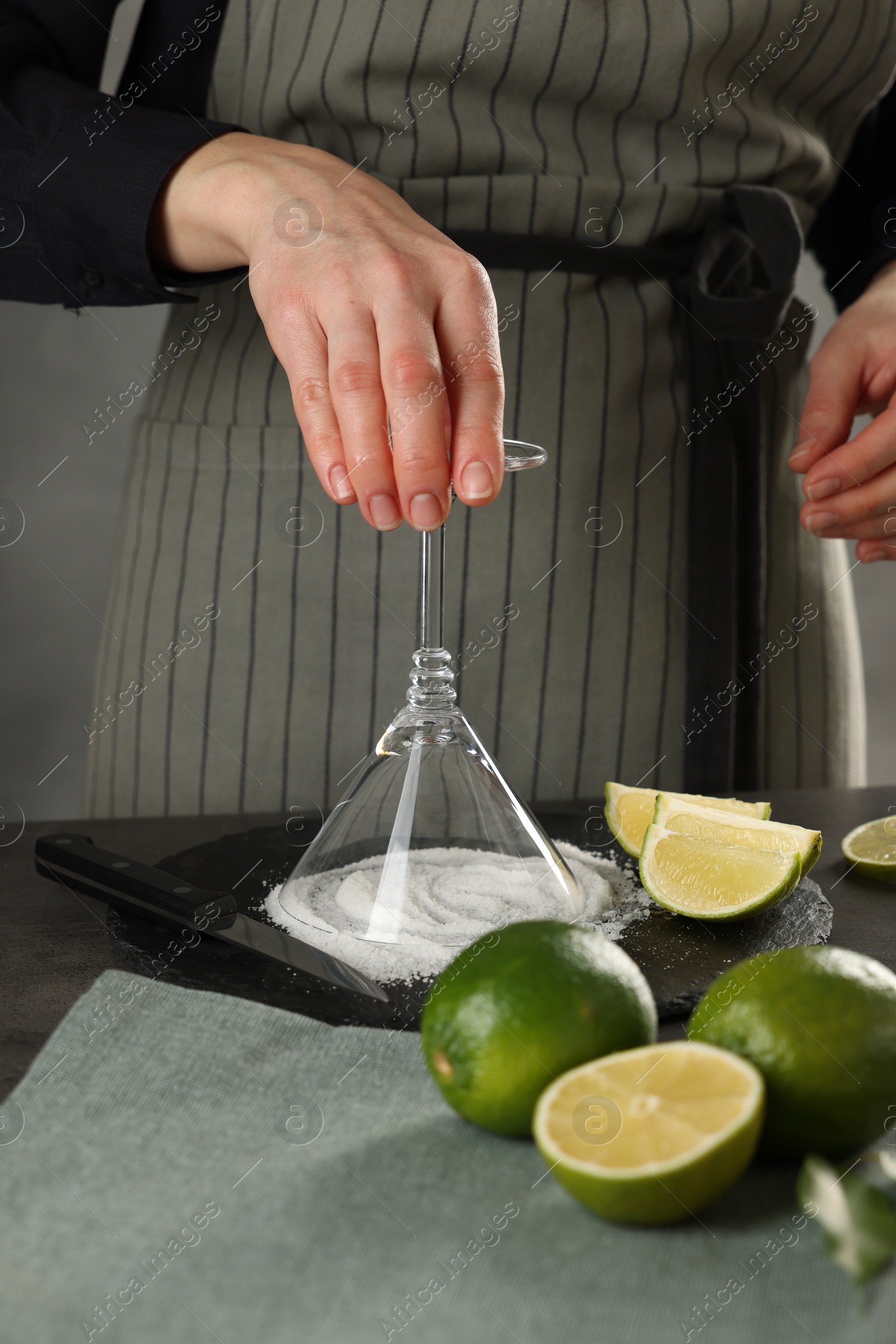 Photo of Woman making delicious Margarita cocktail at grey table, closeup