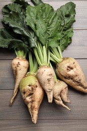 Photo of Fresh sugar beets with leaves on wooden table, flat lay