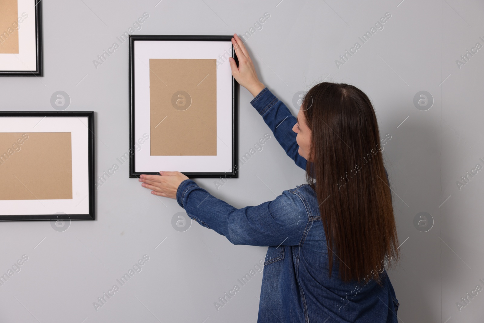 Photo of Woman hanging picture frame on gray wall