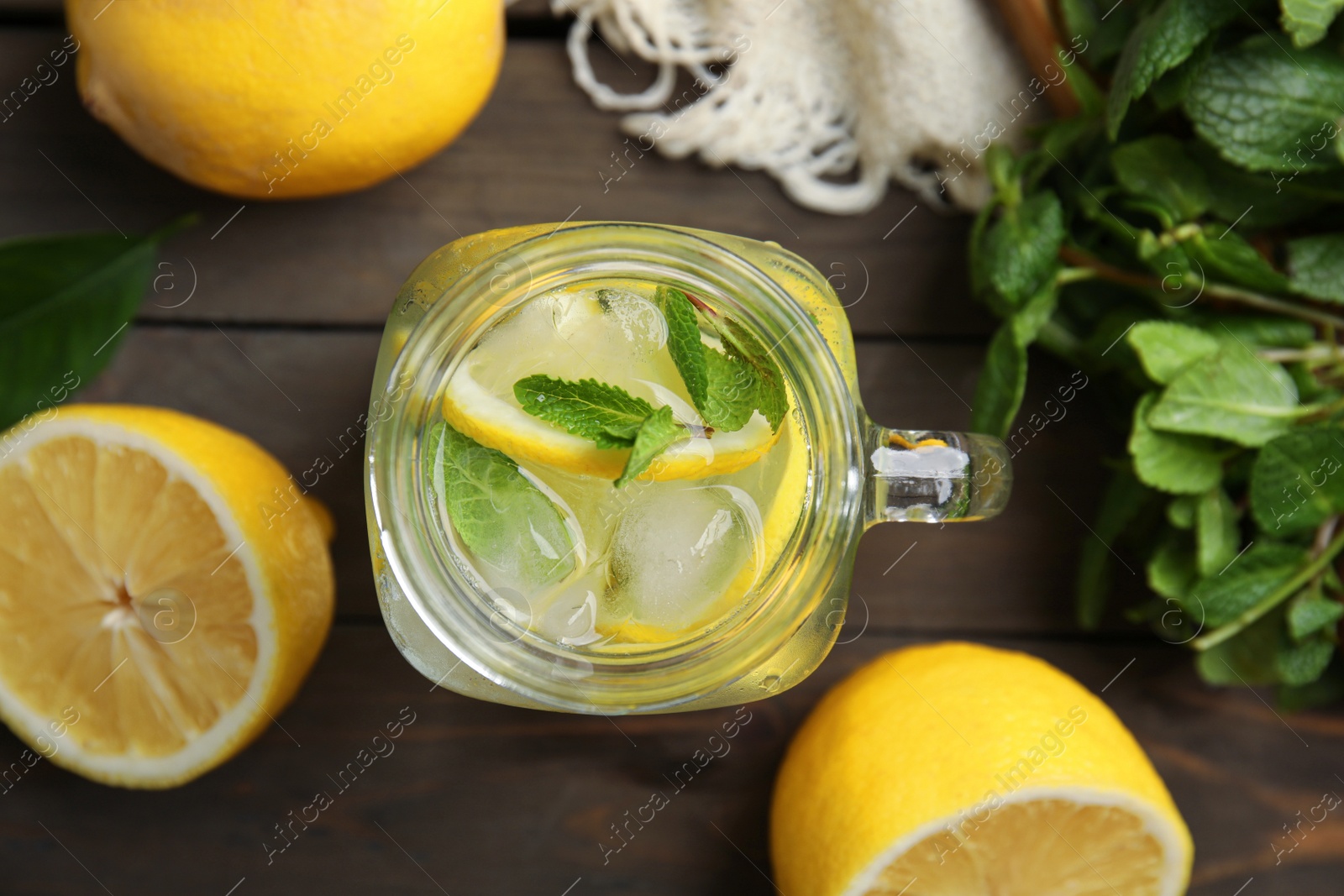 Photo of Mason jar of cold lemonade and ingredients on wooden table, flat lay