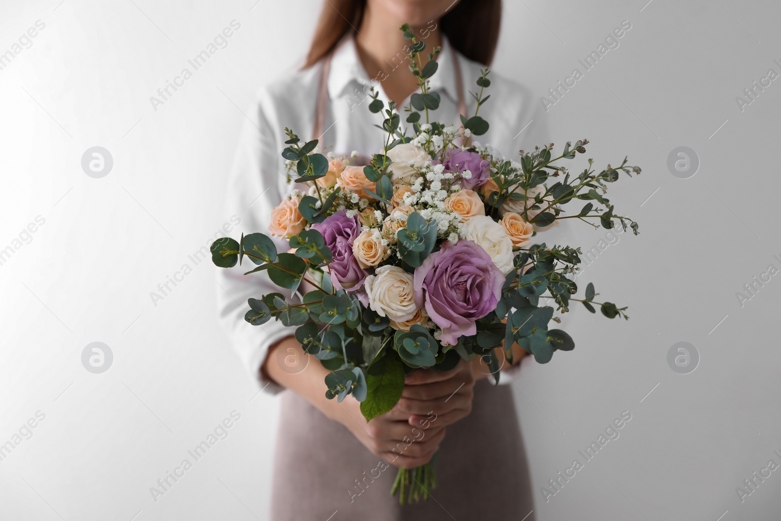 Photo of Florist holding beautiful wedding bouquet on white background, closeup