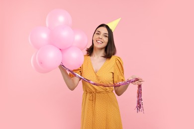 Photo of Happy young woman in party hat with balloons on pink background