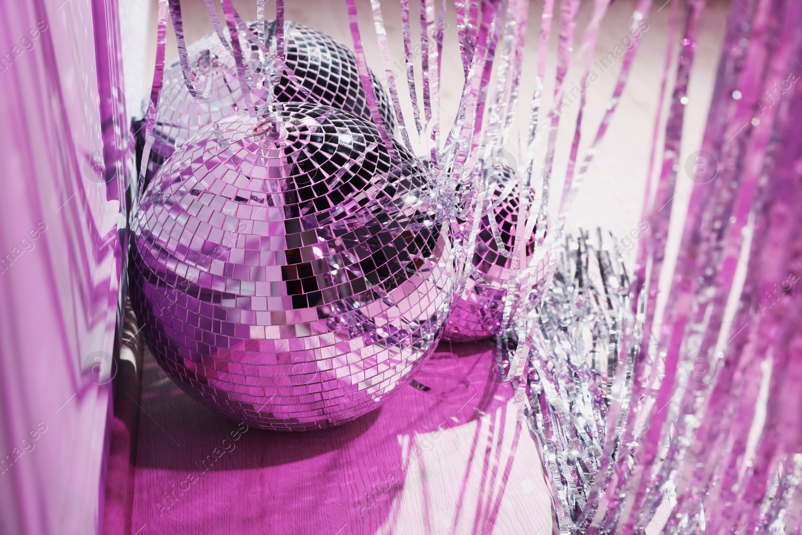 Photo of Shiny disco balls and foil fringe curtain indoors, closeup