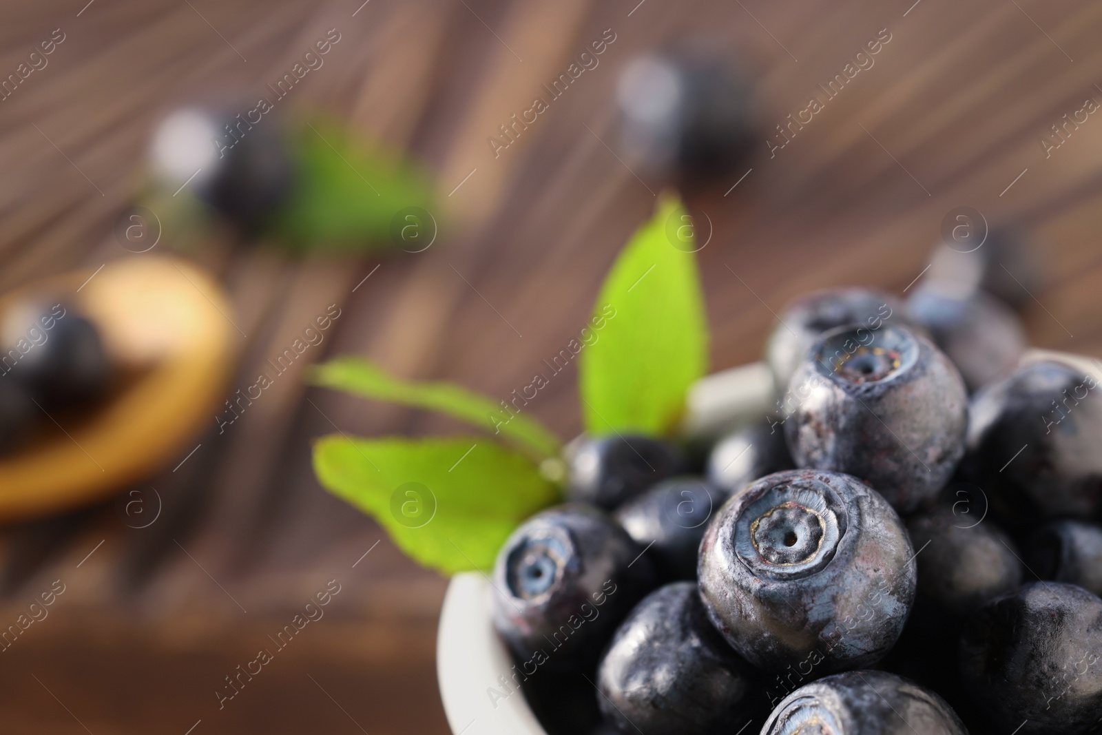 Photo of Tasty fresh bilberries on blurred background, closeup. Space for text