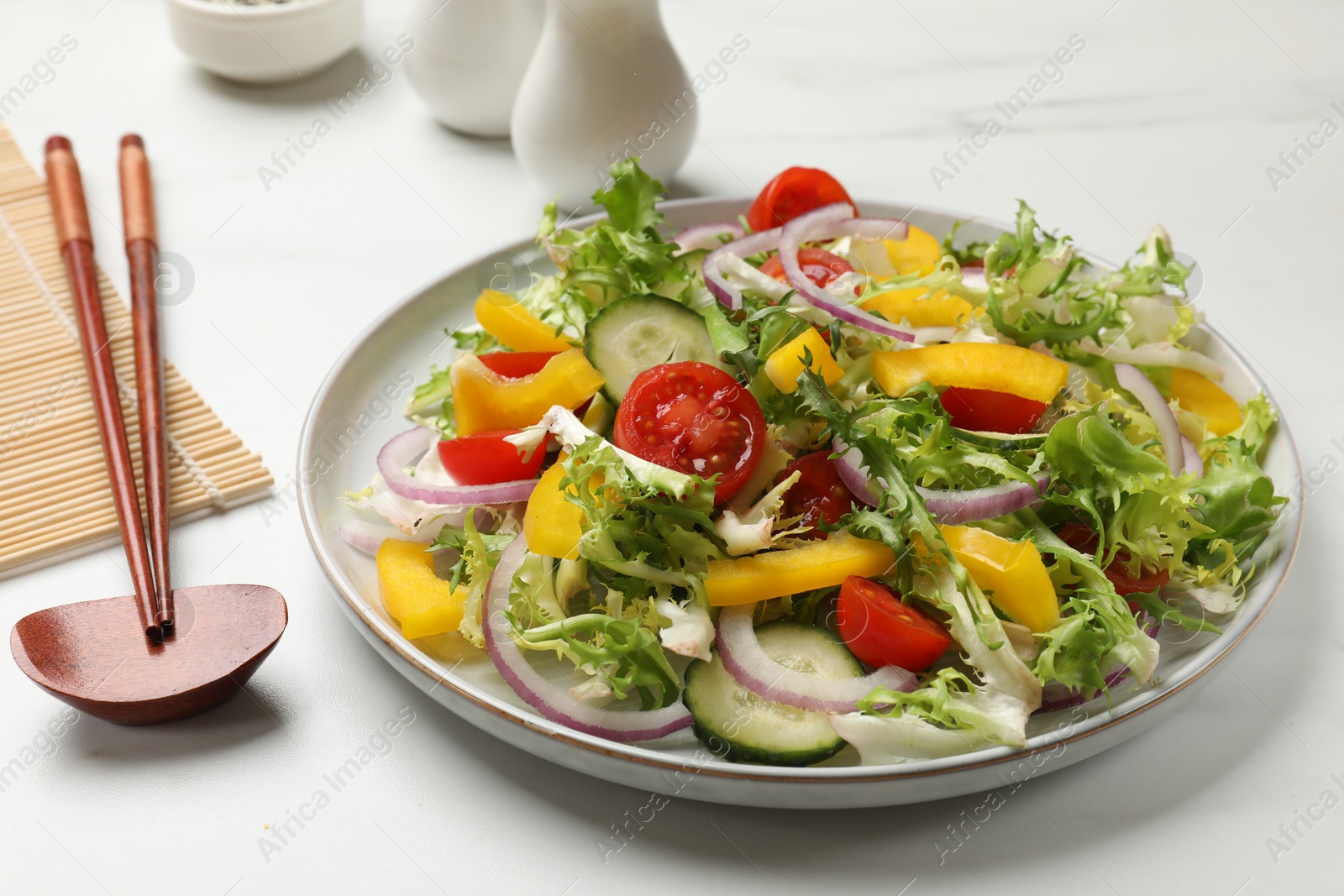 Photo of Tasty fresh vegetarian salad and chopsticks on white marble table, closeup