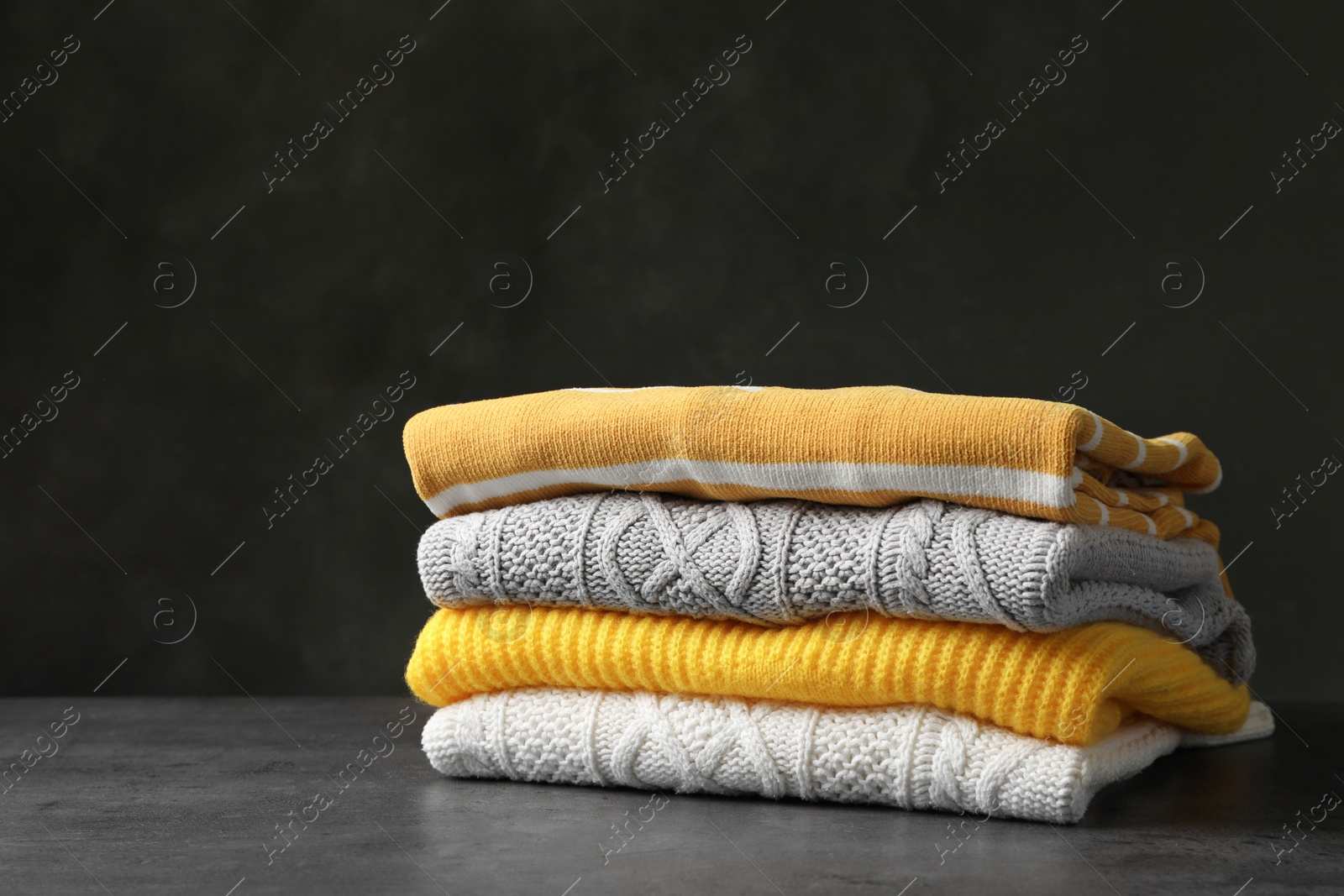 Photo of Stack of folded knitted sweaters on table. Space for text