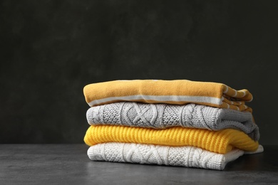 Photo of Stack of folded knitted sweaters on table. Space for text