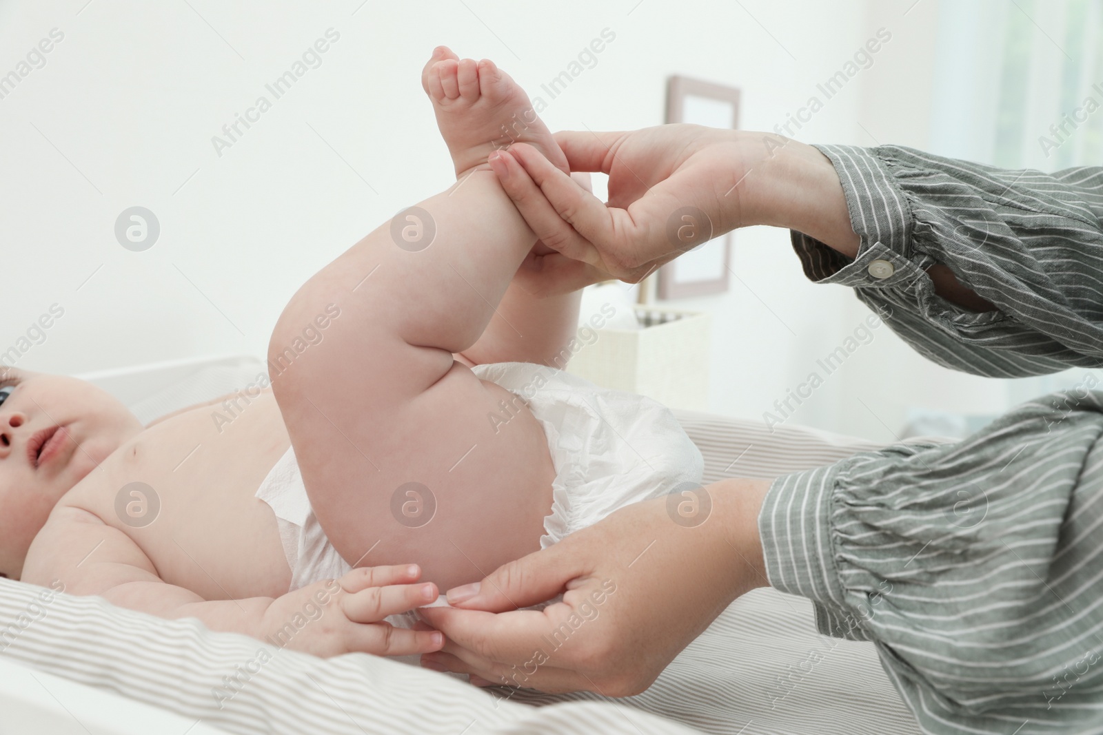 Photo of Mother changing baby's diaper on table at home, closeup