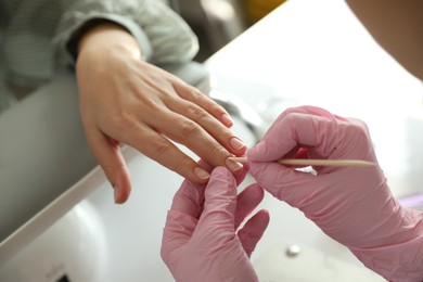 Photo of Professional manicurist working with client in beauty salon, closeup