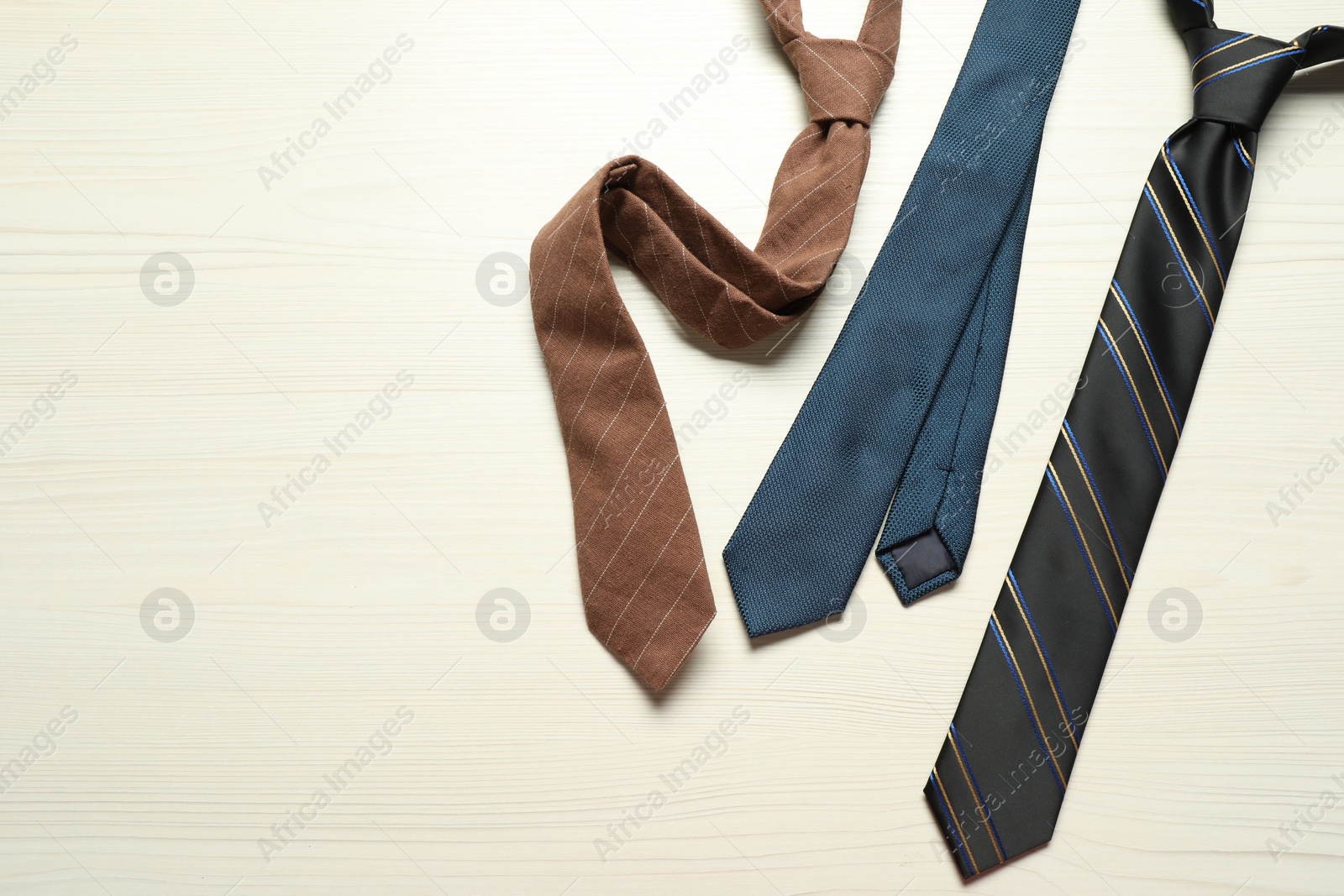 Photo of Different neckties on white wooden table, flat lay. Space for text