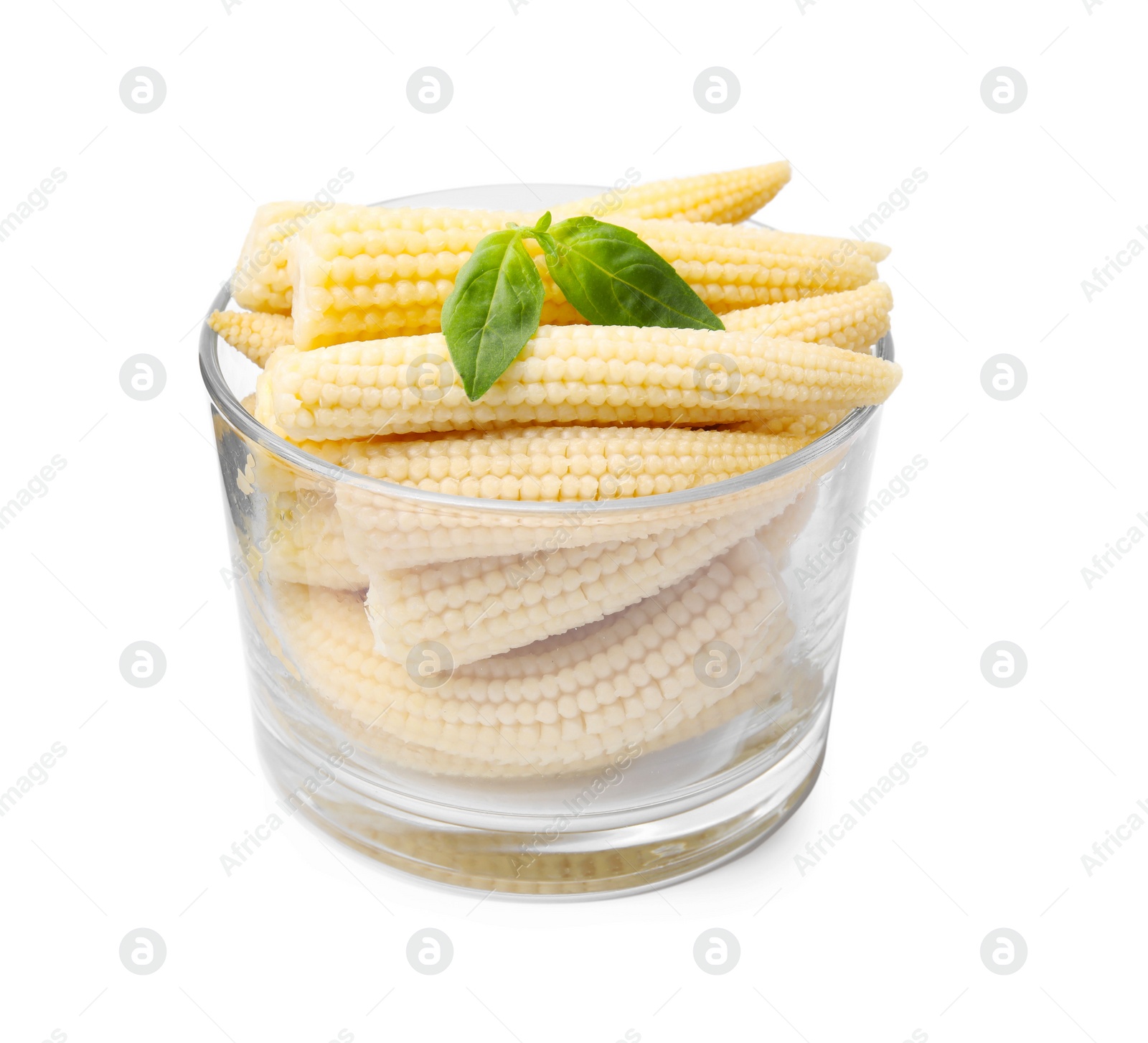 Photo of Canned baby corns with basil in glass on white background