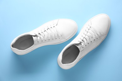 Photo of Pair of stylish white sneakers on light blue background, top view