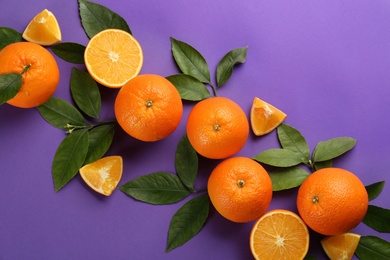 Photo of Delicious oranges on purple background, flat lay