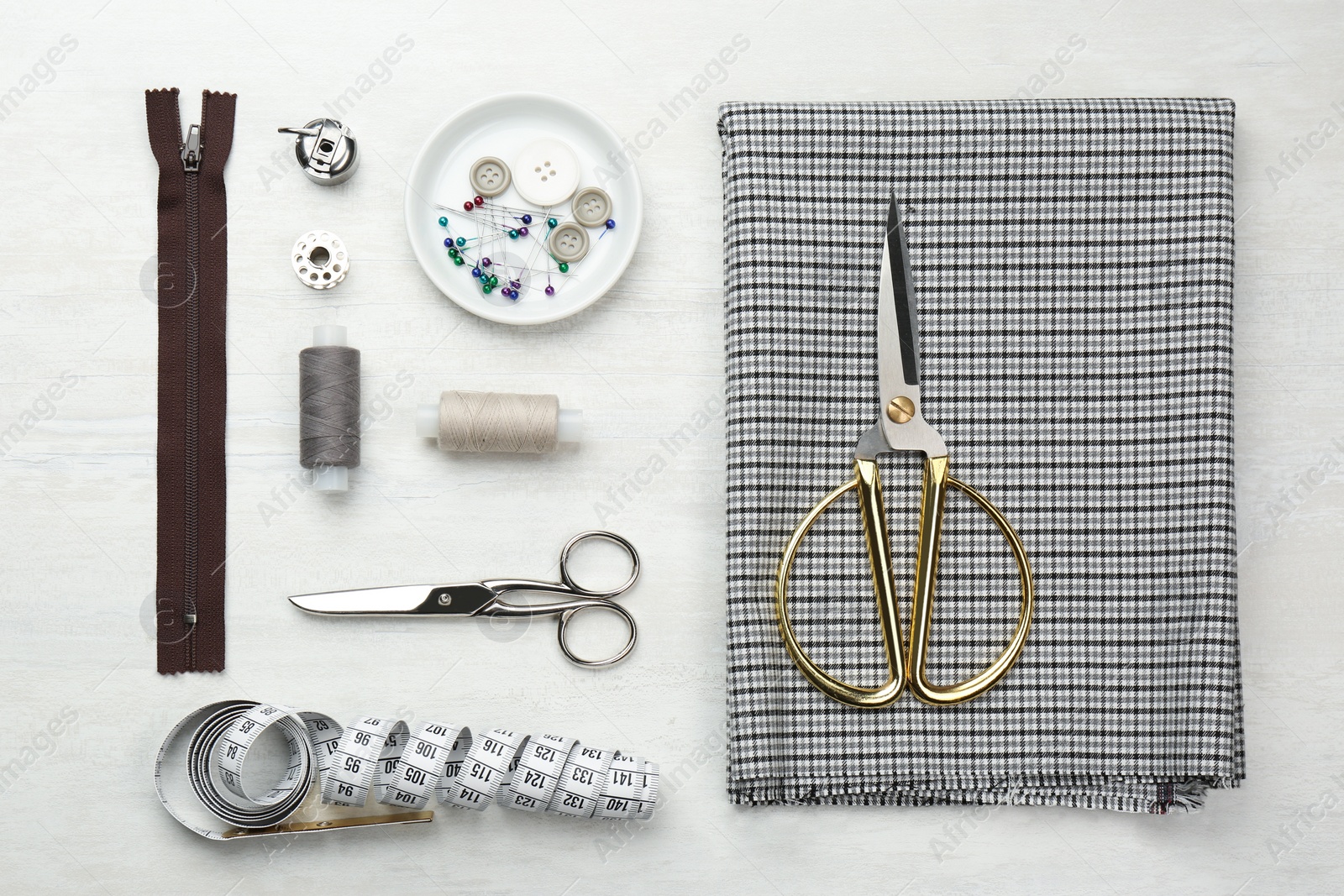 Photo of Flat lay composition with different sewing supplies and fabric on white wooden table