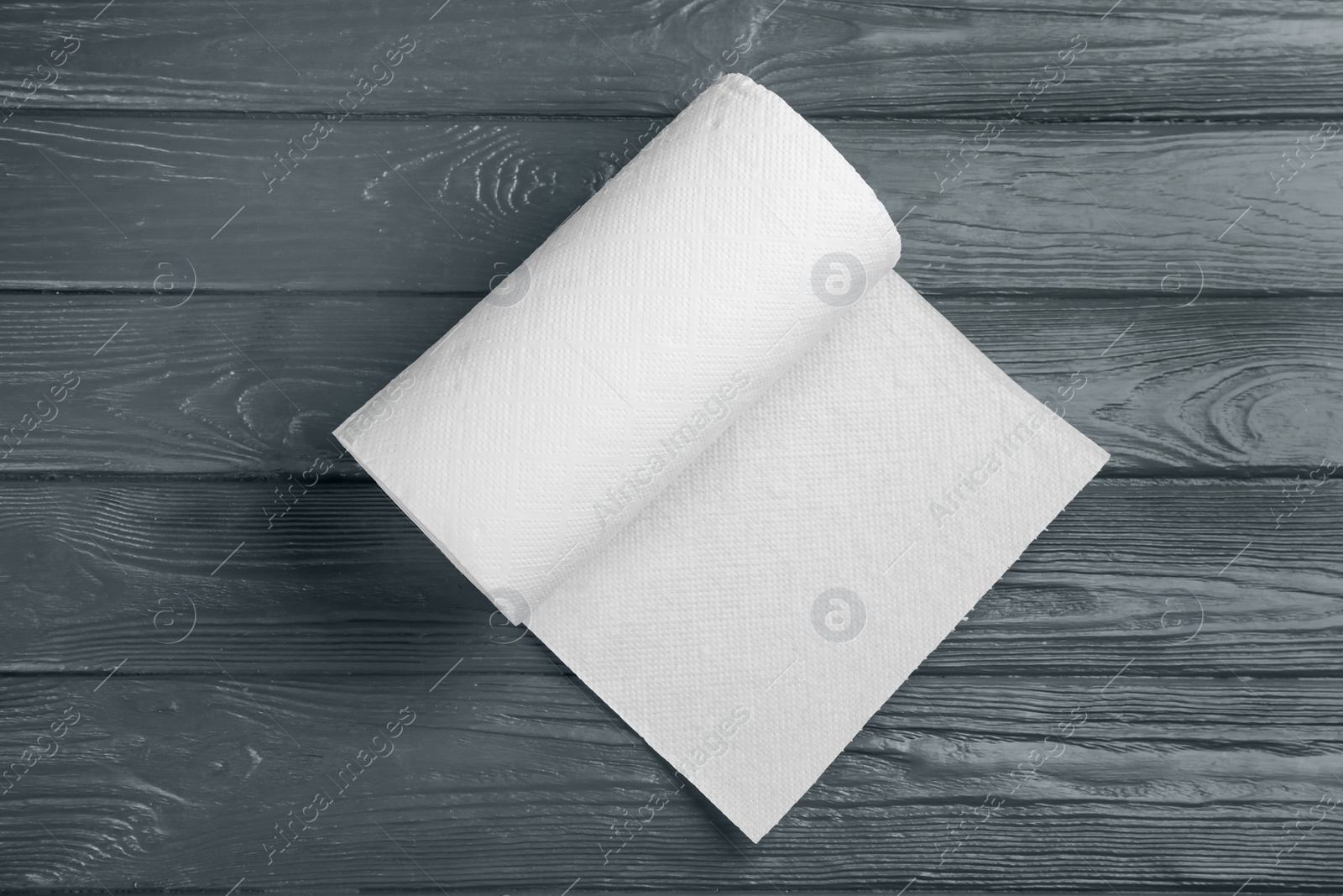 Photo of Roll of paper towels on grey wooden table, top view