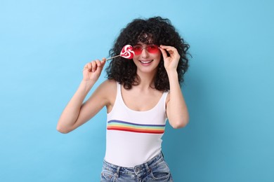 Photo of Beautiful woman in sunglasses with lollipop on light blue background