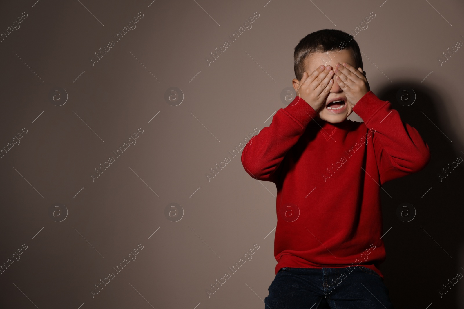 Photo of Scared little boy on beige background, space for text. Domestic violence concept