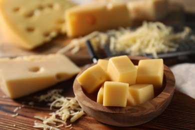 Grated and cut cheese on wooden board, closeup