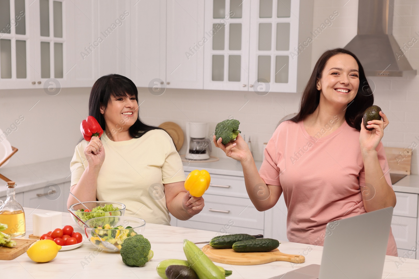 Photo of Happy overweight women having fun while cooking together in kitchen