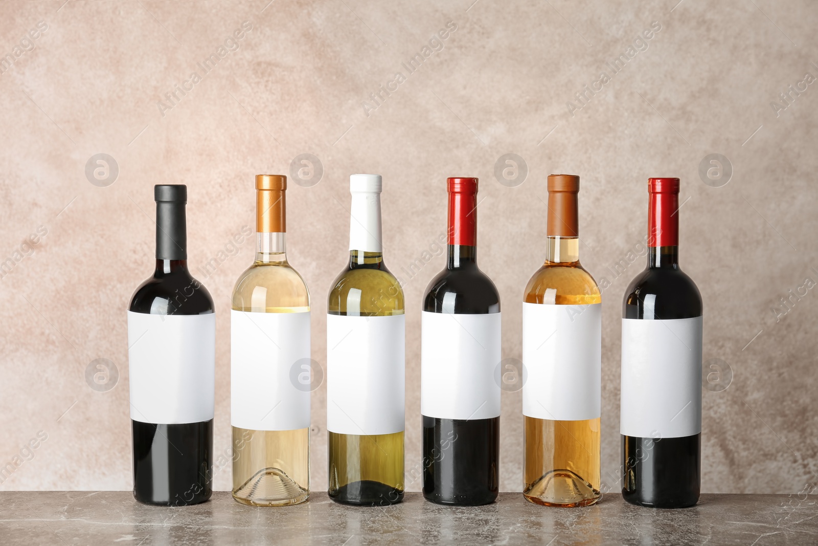 Photo of Bottles with different wine on table against color background