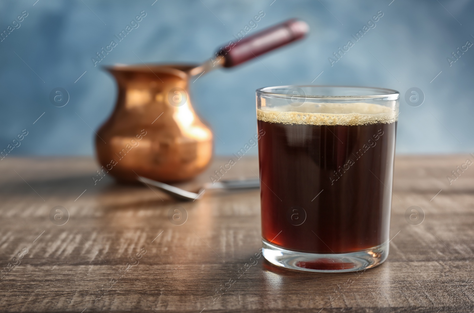 Photo of Glass of aromatic hot coffee on wooden table