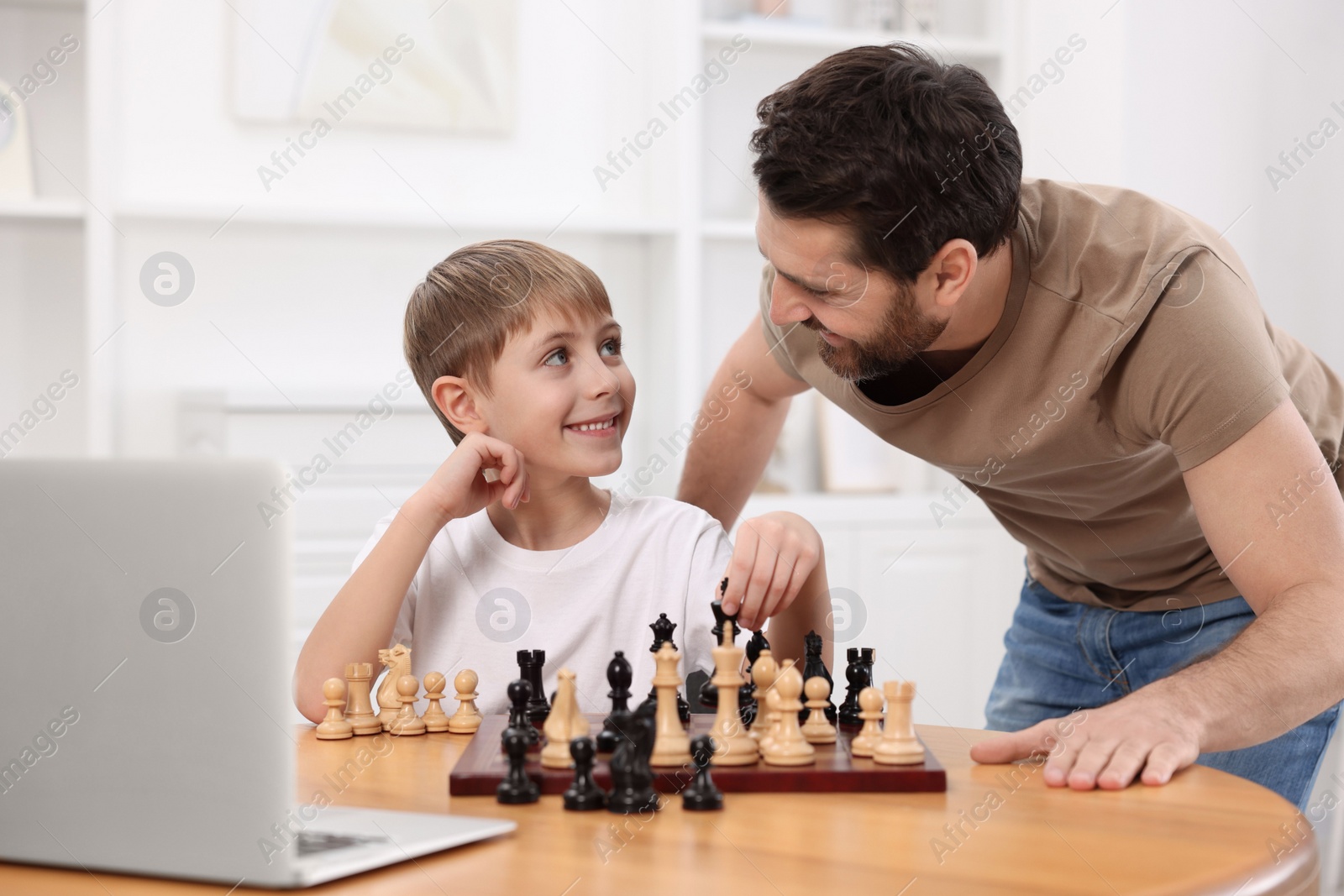 Photo of Father teaching his son to play chess following online lesson at home