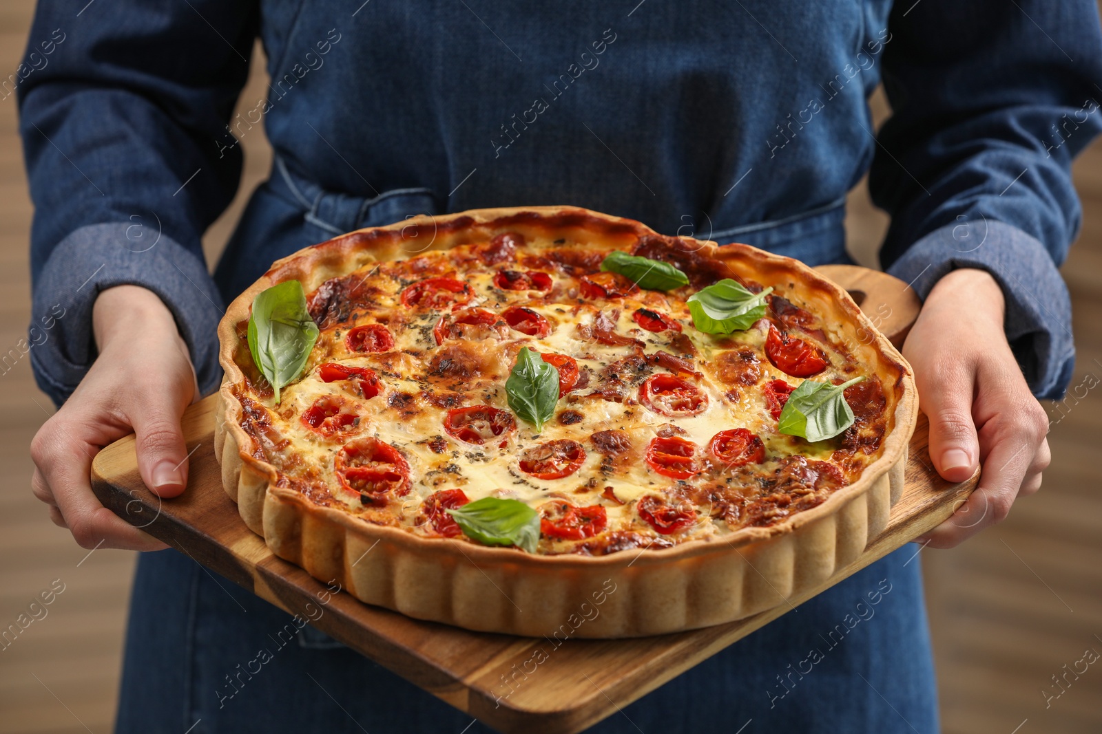 Photo of Woman holding delicious homemade quiche with prosciutto, closeup