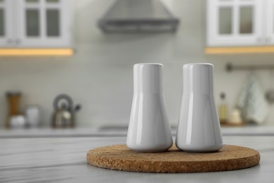 Photo of Ceramic salt and pepper shakers on white marble table in kitchen. Space for text