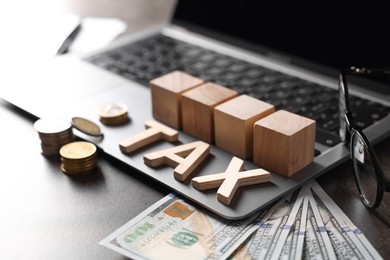 Photo of Word Tax made of wooden letters, cubes, laptop, banknotes and coins on grey table