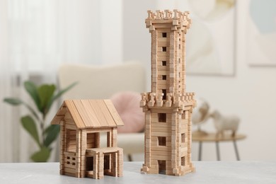 Photo of Wooden tower and house on light grey table indoors. Children's toys
