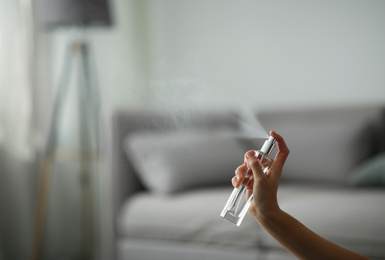 Photo of Woman spraying air freshener indoors closeup. Space for text