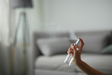 Woman spraying air freshener indoors closeup. Space for text