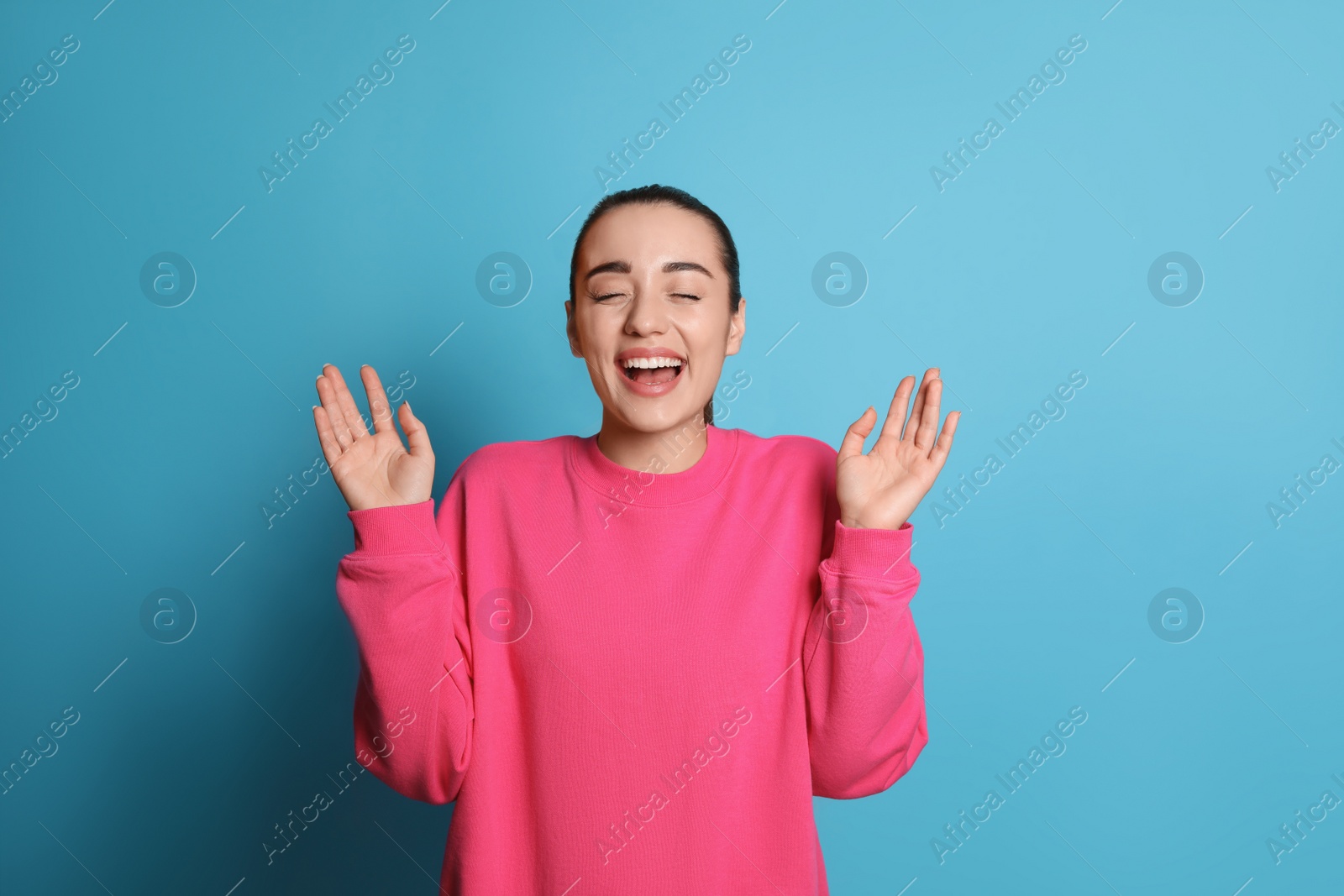 Photo of Beautiful young woman laughing on light blue background. Funny joke