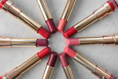 Photo of Set of bright lipsticks on grey background, flat lay
