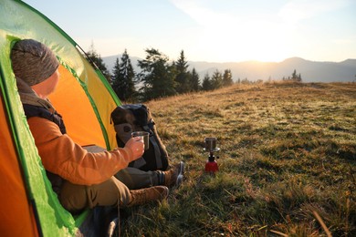Photo of Man with cup of hot drink in camping tent. Space for text