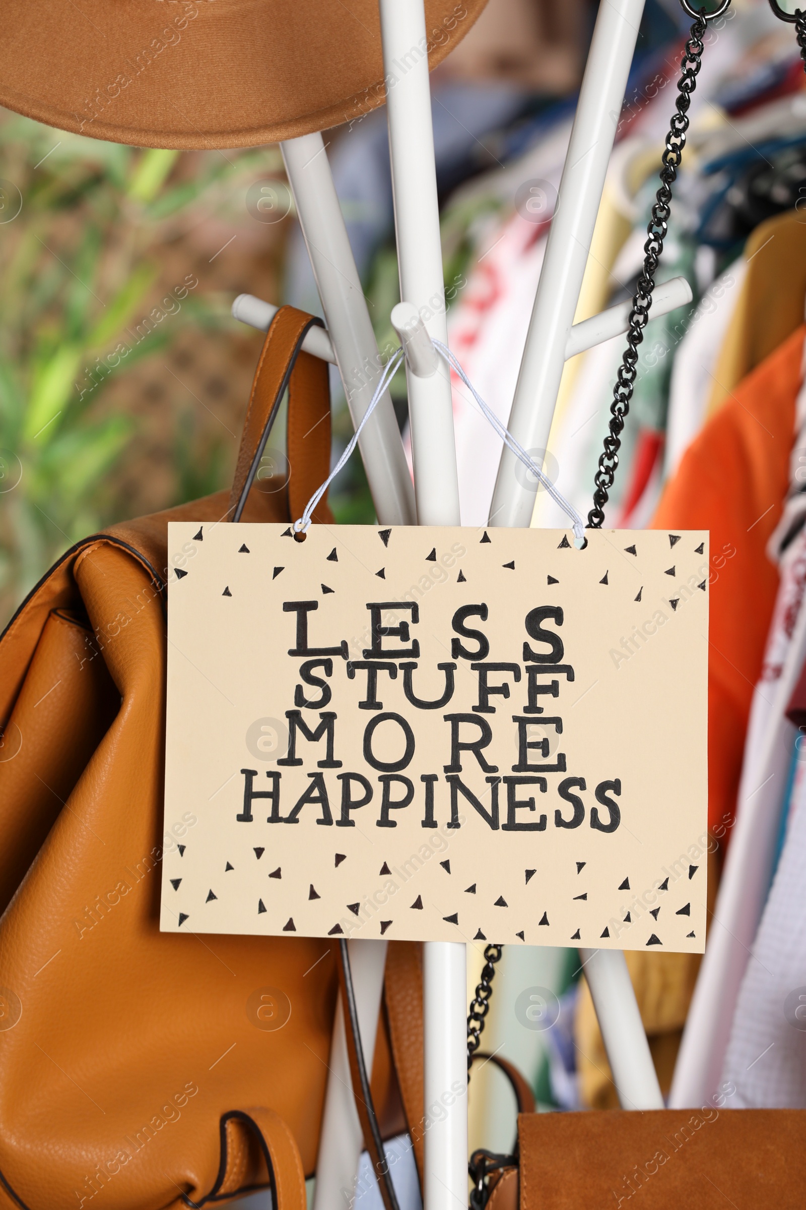 Photo of Plate with words Less Stuff More Happiness near bags and clothes