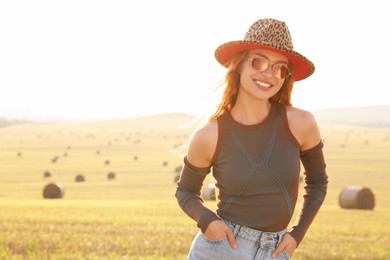 Beautiful happy hippie woman in hat in field, space for text