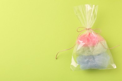 Photo of Packaged sweet cotton candy on green background, top view. Space for text