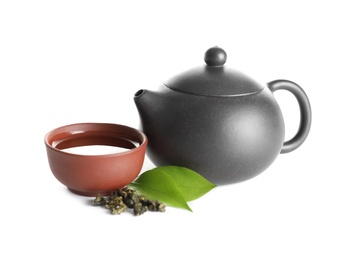 Photo of Teapot near cup of Tie Guan Yin oolong and leaves on white background