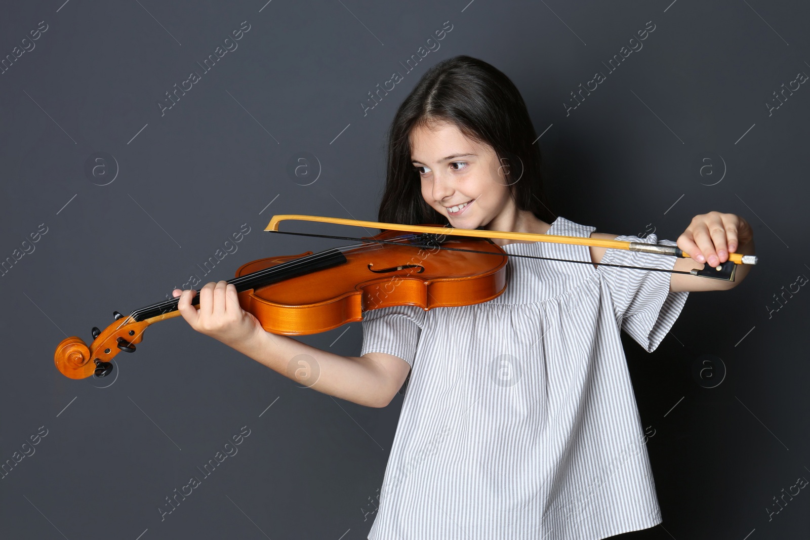 Photo of Preteen girl playing violin on black background