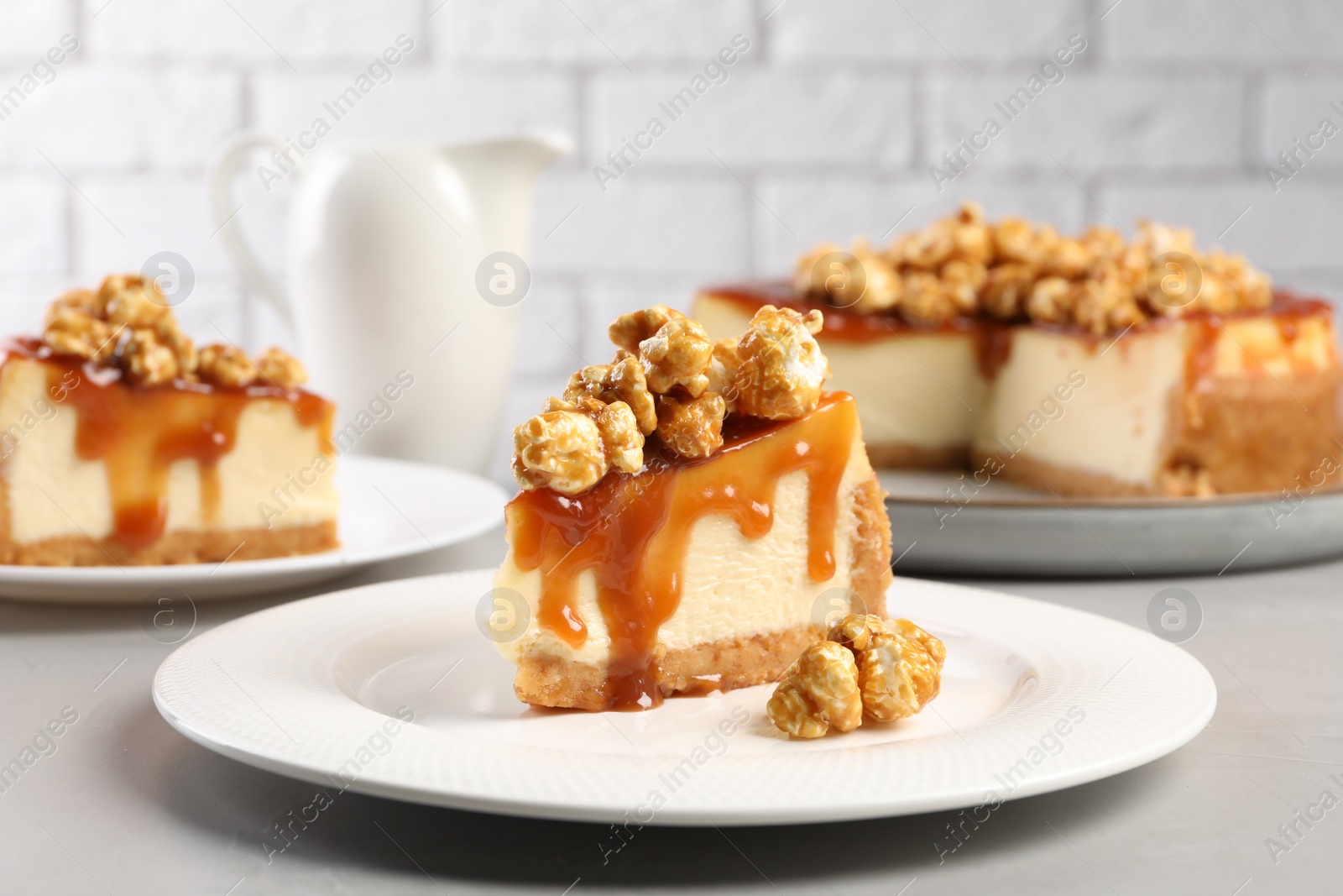 Photo of Piece of delicious caramel cheesecake with popcorn on light grey table